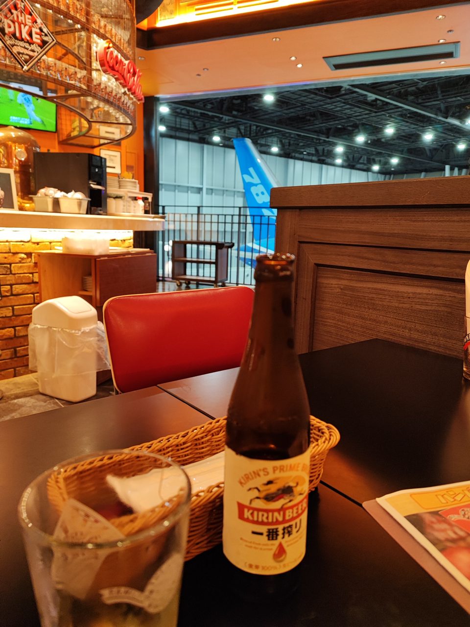 テーブル越しに見える787の尾翼とビール